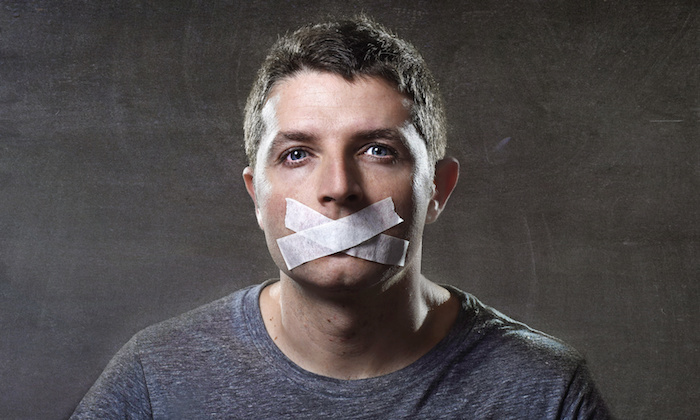 attractive young man with mouth sealed on duct tape to prevent him from speaking