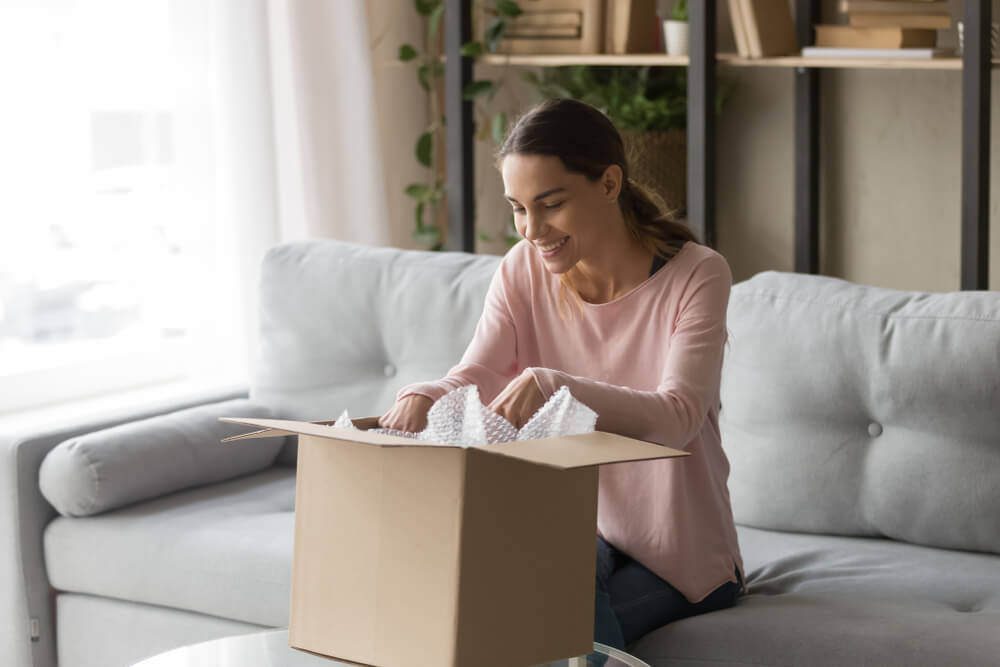 cliente recebendo encomenda em caixa com expressão feliz