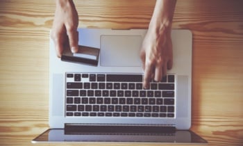 Hands holding credit card and using laptop. View from above