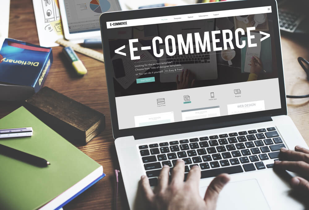 laptop em mesa com materiais de escritorio com palavra e-commerce em tela