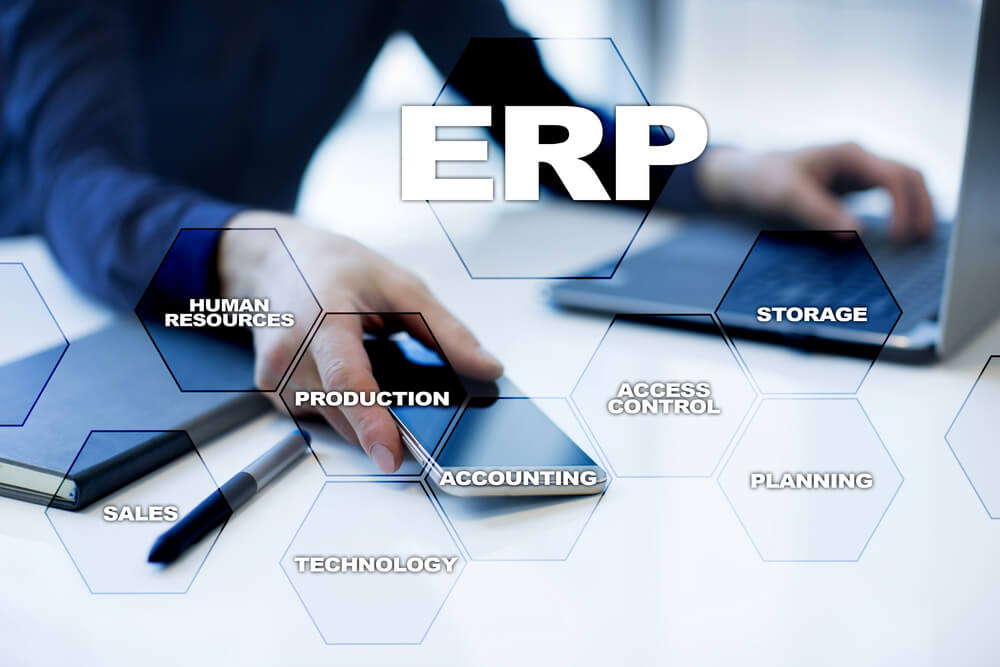 mão de executivo em mesa de escritório segurando smartphone com termos relacionados a ERP