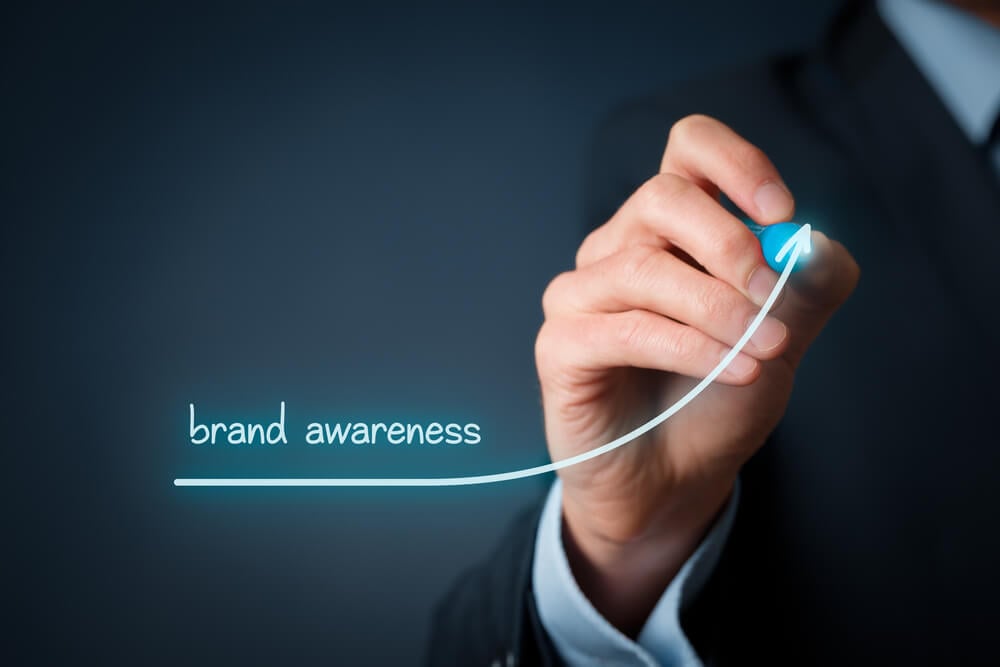 mão masculina de profissional assinalando símbolo de crescimento e título brand awareness