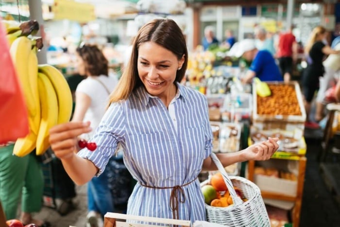 mulher sorrindo andando em uma feira de supermercado