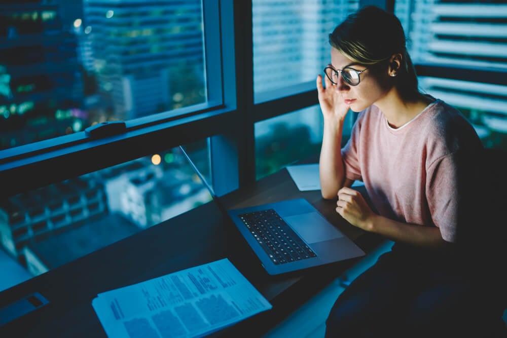 moça concentrada em escrtório a frente de laptop
