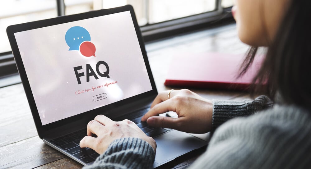 mulher com laptop em mesa com lustraçao da palavra FAQ 