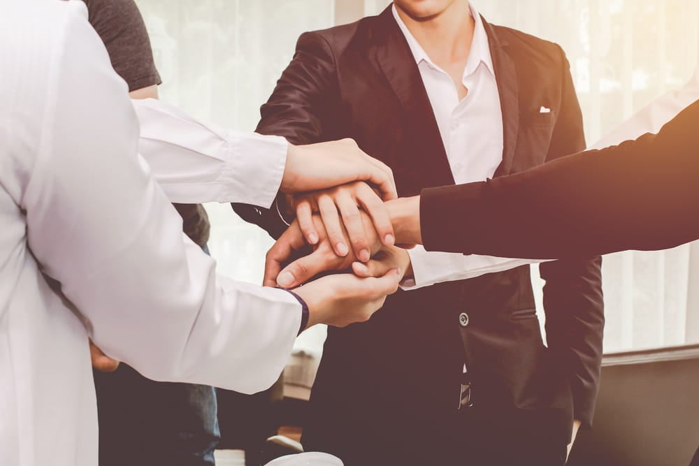 profissionais na area de marketing com maos juntas simbolizando trabalho em equipe