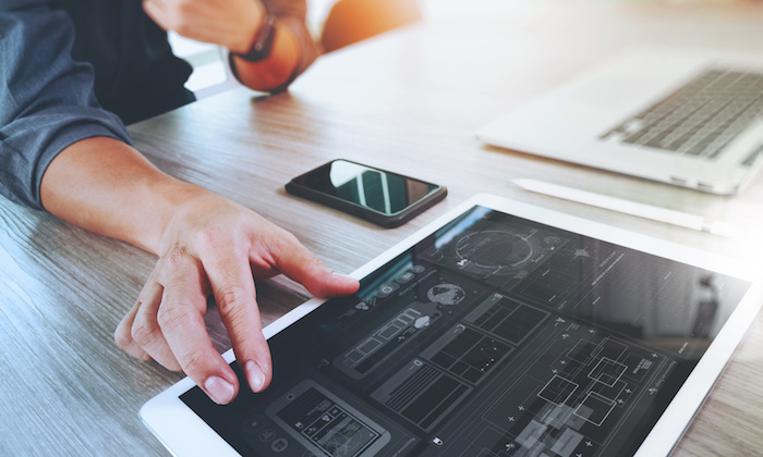 Website designer working digital tablet and computer laptop with smart phone and digital design diagram on wooden desk as concept