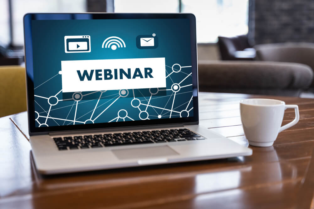 título webinar em tela de laptop junto de xícara em mesa