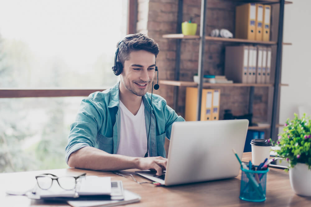 vendedor com earphone e microfone em frente a laptop